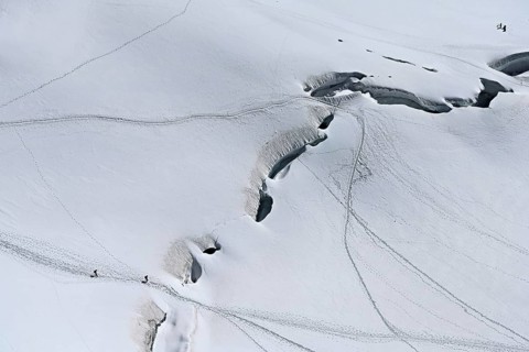A group of mountaineers runs across a snow-covered mountain, Aiguille du Midi, Chamonix-Mont-Blanc,