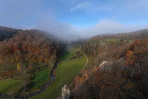 Autumn landscape with rising fog over the Grosse Lauter river loop in Lautertal at sunrise. View