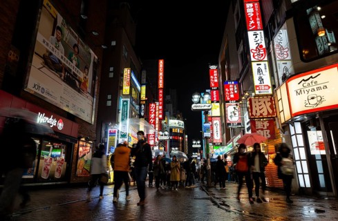 Busy pedestrian zone with many shopping centers and stores, illuminated with lots of neon signs at