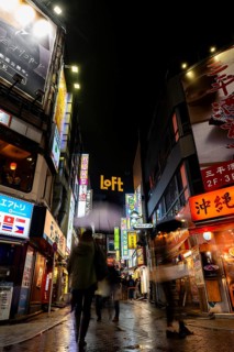Busy pedestrian zone with many shopping centers and stores, illuminated with lots of neon signs at