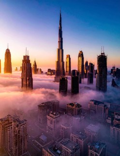 City scape emerging from a dense enveloping fog in sunrise and skyscrapers piercing the haze, big