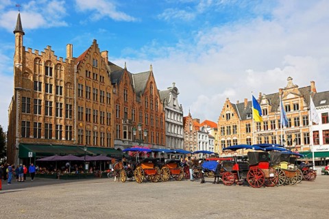 Historic houses on the market square in the old town of Bruges with horse-drawn carriages, Grote