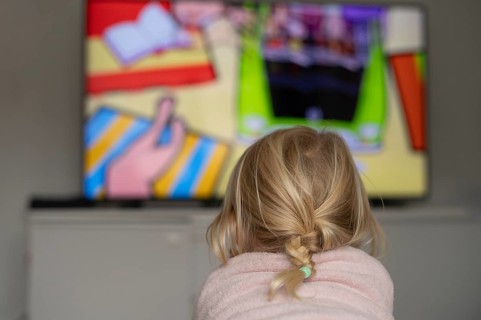 Child, girl, 4 years old, blonde, lying on sofa, watching TV, watching television, in front of