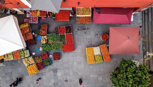 Traditional Mexican plaza with crates of peppers, onions, and tomatoes, economic prosperity in