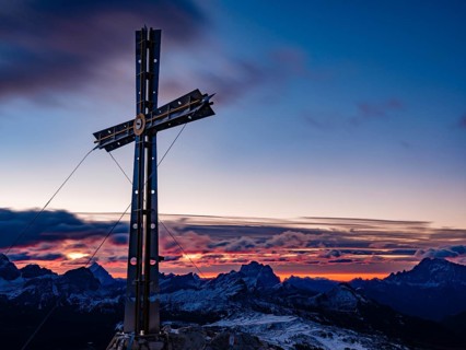 Sassongher summit cross at dawn, in the background Monte Cristallo, Monte Pelmo and Civatta,