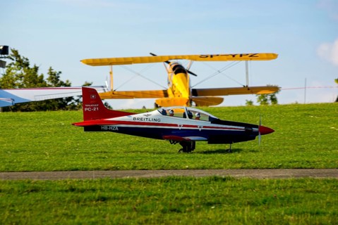 An RC model of a Pilatus PC-21 with advertising for the Swiss watch brand Breitling during a flight