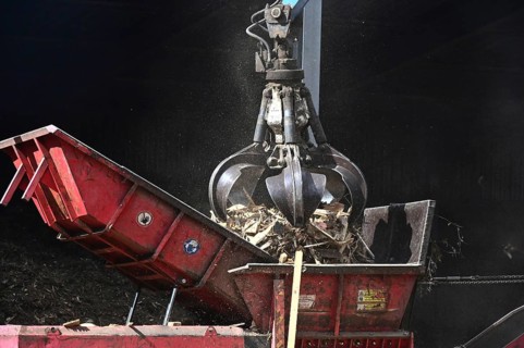 Loading crane with grab arm for loading wood waste for wood pellet production on the premises of