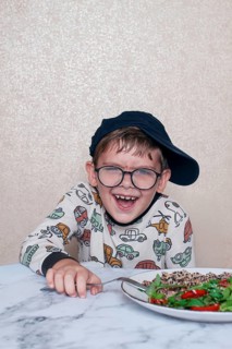Child reacts dramatically to a salad served on a marble table at home during lunchtime, A little
