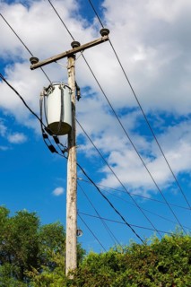 Electricity transformer, high voltage transmission wires, internet, telephone cables attached to