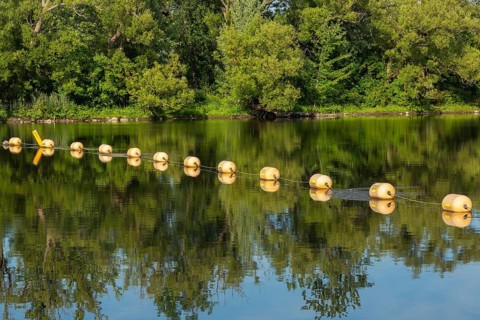 String of yellow cautionary navigation marker buoys on water surafce of river serving to warn,