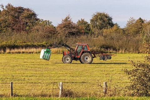 Tractor transporting bales of silage wrapped in film, Falshöft, Pommerby, Schleswig-Holstein,