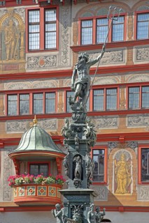 Neptune fountain with sculpture of Neptune Roman god of the sea with trident on the house facade