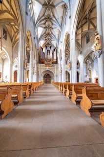 Impressive nave with organ and symmetrically arranged wooden benches under a vaulted ceiling, St