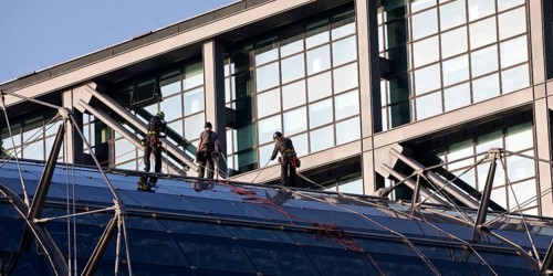 Three male glass cleaners abseiling down a glass roof of Berlin Central Station to clean windows,