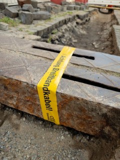 Flapping tape with the indication of an installed fibre optic cable at a construction site in