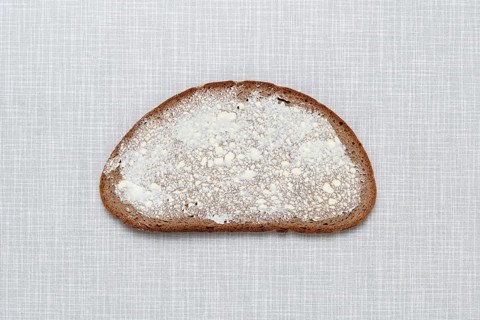 Top shot of a slice of bread smeared with margarine on a white Resopal plate