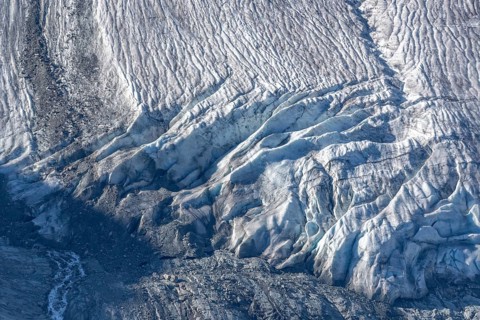 Intricate patterns of ice and rock are showcased in this stunning glacial landscape, revealing the