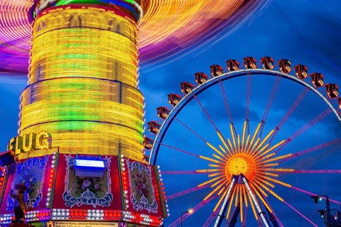 Illuminated chain carousel in motion, behind the Ferris wheel at standstill, Festwiese,