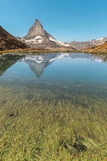 The sharp peak of Matterhorn rises majestically above a serene alpine lake, reflecting perfectly on
