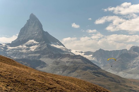 A person paraglides against the stunning backdrop of the Matterhorn mountain in Switzerland. The