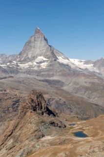 The towering peak of the Matterhorn dominates the clear sky, surrounded by rocky terrain and