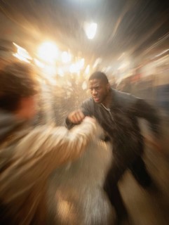 A man gets into a fighting stance, surrounded by dynamic movement and a background filled with
