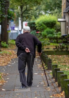 Elderly man going for a walk with the help of a walking stick, North Rhine-Westphalia, Germany