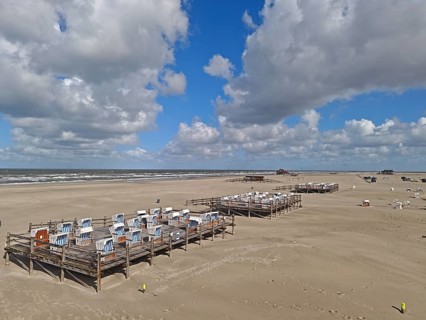 North Sea beach, blue sky, white clouds, summer, sun, sand, beach chairs on a platform, on the edge