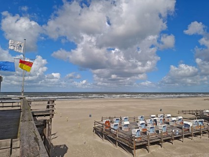 North Sea beach, blue sky, white clouds, summer, sun, sand, beach chairs on pedestal, flags, on the