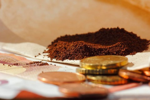 Ground coffee in a filter bag with coins and a ten euro note in front of it, North