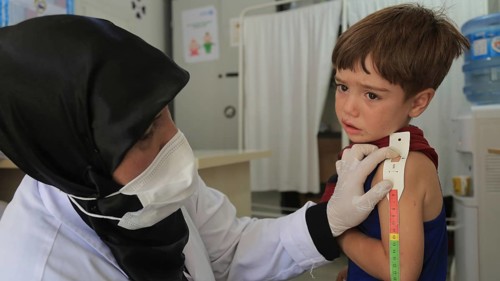 A doctor examines children's malnutrition inside a refugee camp. Malnutrition was measured using a