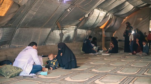 A doctor examining a woman inside a mobile medical point dedicated to treating Syrian refugees.