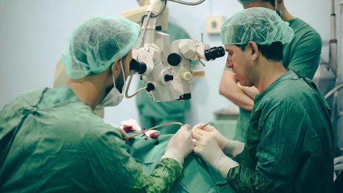 Several doctors performing a complex surgical operation inside an operating room for a displaced