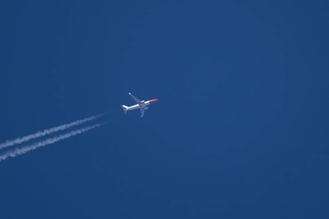 Boeing 737 jet passenger aircraft of Norweign Air with a vapour trial or contrail behind flying in