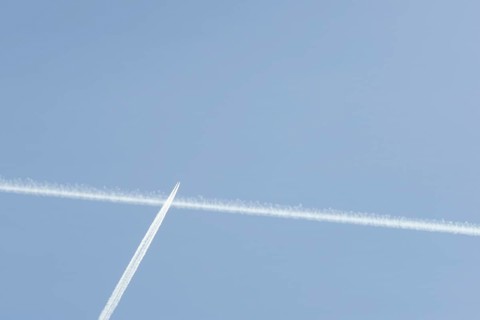 Jet passenger aircraft with a vapour trail or contrail flying in a blue sky, England, United