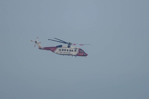 Sikorsky S-92A helicopter of the UK HM Coastguard flying in a blue sky, England, United Kingdom
