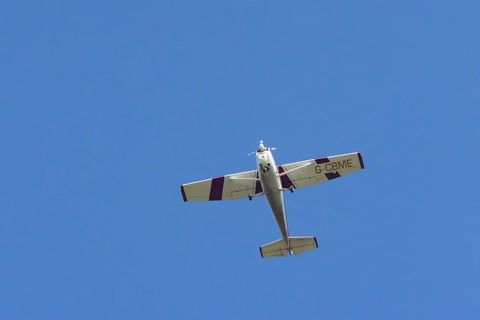 Reims Cessna F172M Skyhawk light aircraft flying in a blue sky, England, United Kingdom