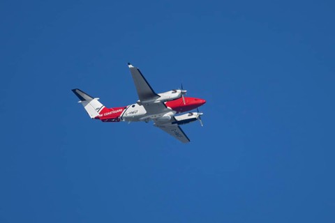 Beech King Air 350 light aircraft of the UK HM Coastguard flying in a blue sky, England, United