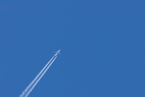 Jet passenger aircraft with a vapour trail or contrail flying in a blue sky, England, United