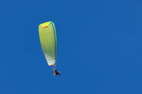 Paraglider flying in a blue sky, England, United Kingdom