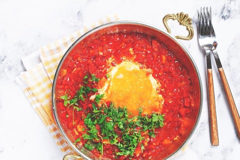 Traditional Turkish dish, scrambled eggs with tomatoes, Menemen, with herbs, in a frying pan,