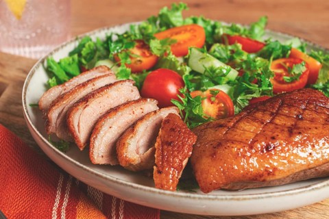Delicious grilled duck breast served with fresh garden salad and cherry tomatoes at a rustic dining