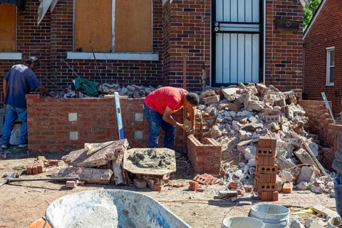 Detroit, Michigan - Workers rebuild the front porch of a house they are remodeling in the