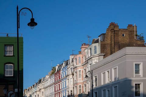 Terraced houses, townhouses with different, colourfully painted facades under a blue sky,