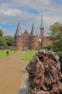 Lion figure at the historic Holstentor and St. Peter's church tower in Lübeck, Brick Gothic, Brick