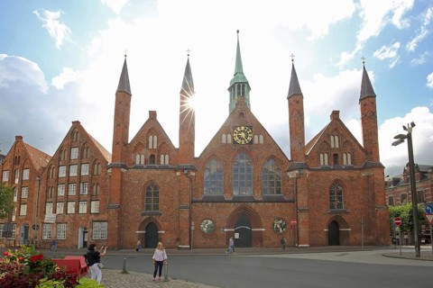 Holy Ghost Hospital backlit with pointed towers, Brick Gothic, Brick building, Old Town, Lübeck,