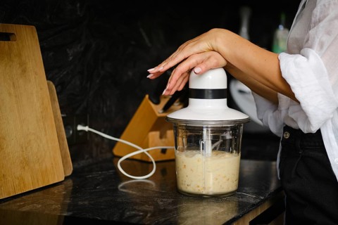 Close-up view of blending ripe bananas and sea buckthorn berries in a stylish kitchen. The focus is