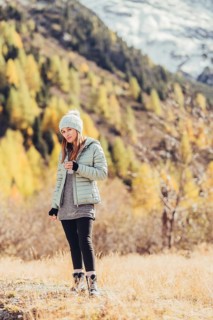 Woman in winter clothes in autumn Engadine with golden trees in Switzerland
