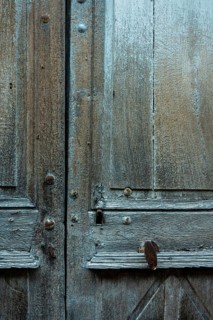 Weathered wooden doors exhibit intricate textures and aged details in an old building. The natural