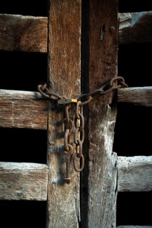 The wooden door, weathered and aged, is closed off with rusty chains, creating an intriguing